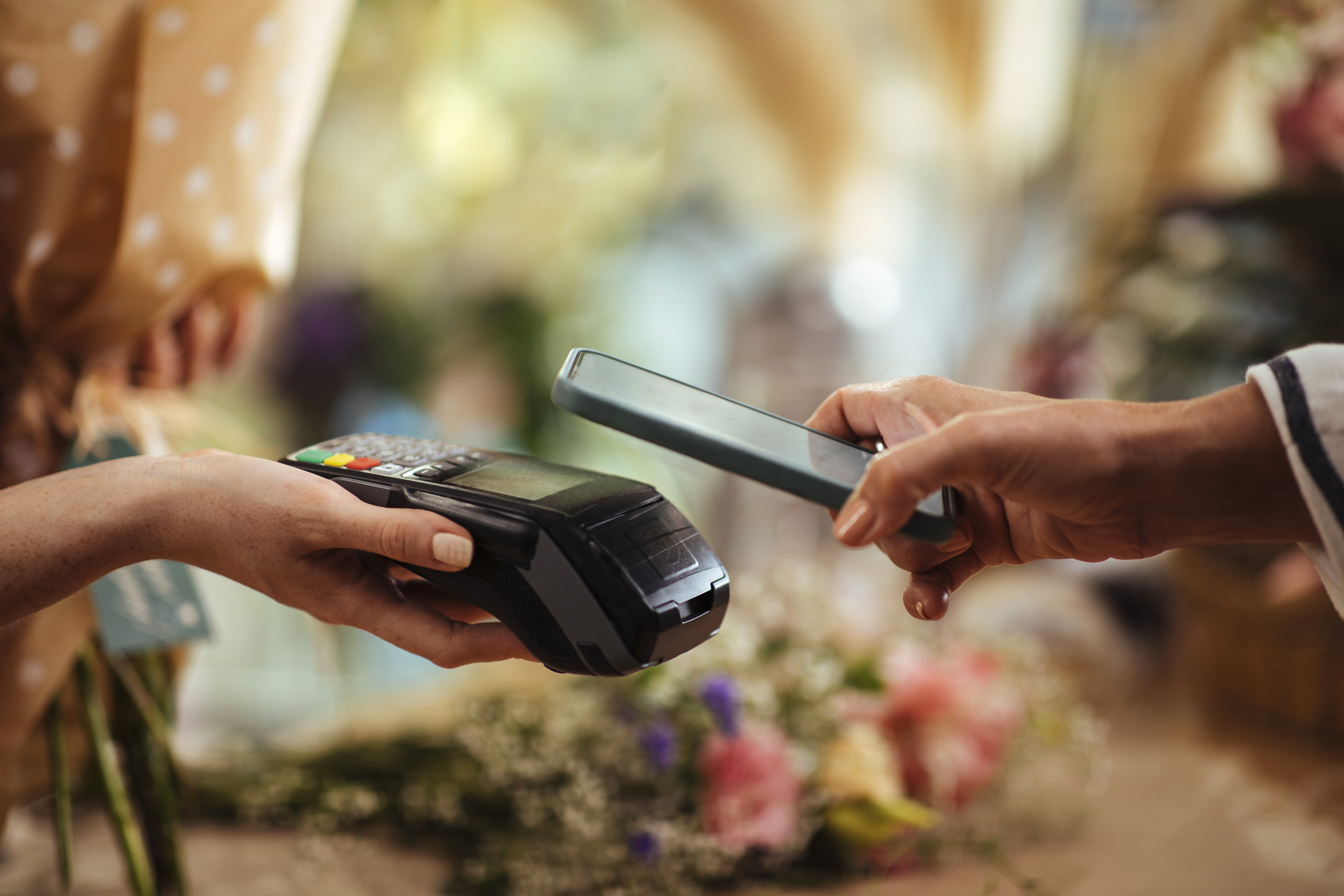 Person betaler kontaktløst med mobilen i butikk.